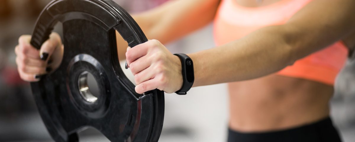 Mulher pegando anailha na mão na academia
