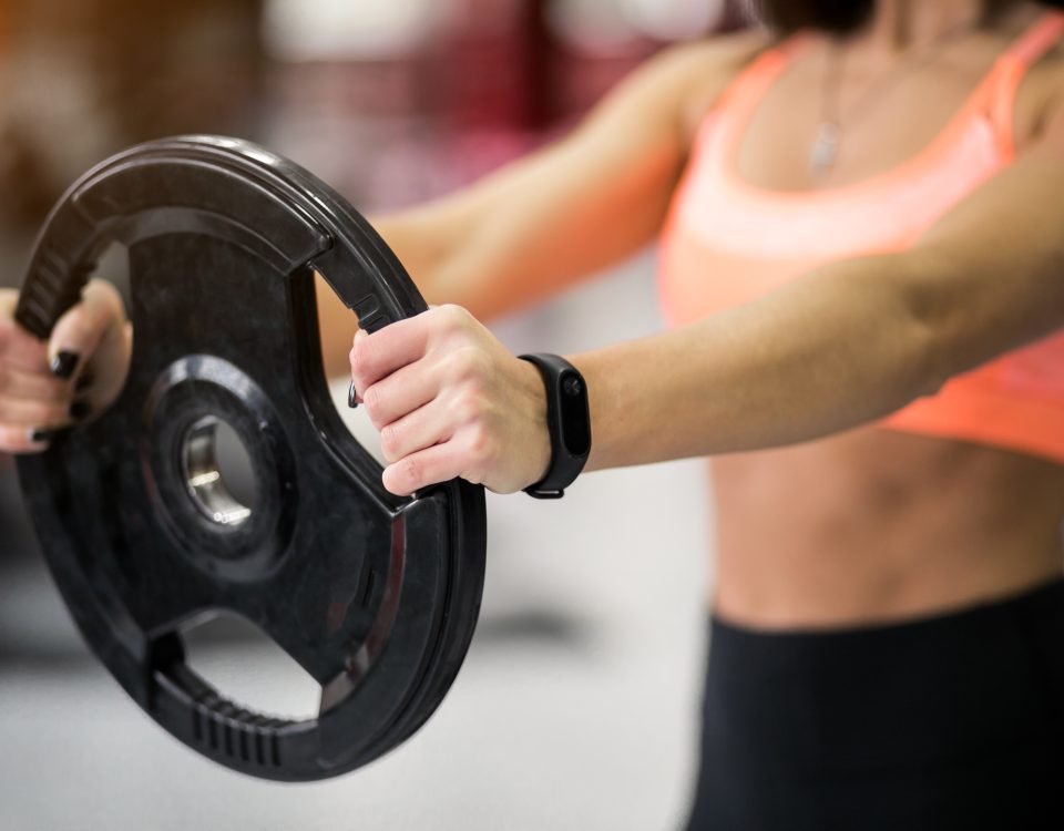 Mulher pegando anailha na mão na academia